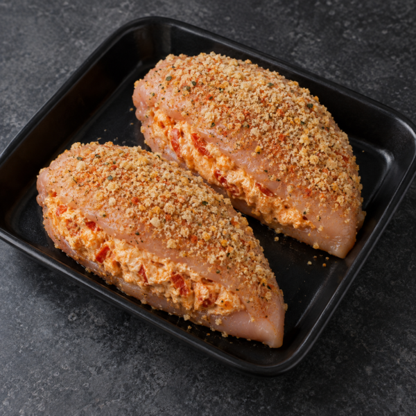 Illustrative image of two raw paprika chicken breasts with cream cheese filling on a black butcher tray
