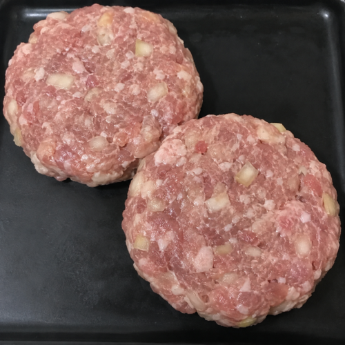 Illustrative image of raw pork and apple burgers on a black butcher’s tray